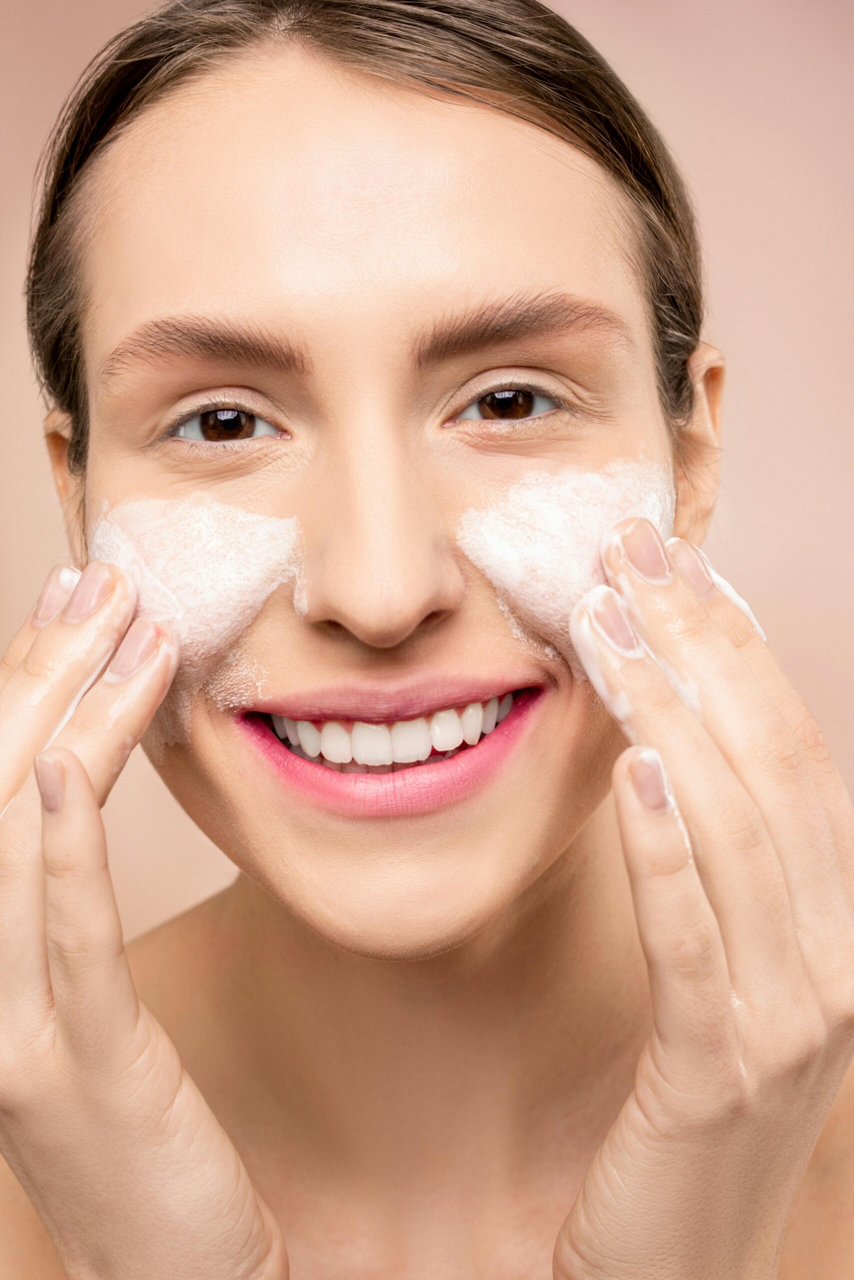 Close-up of a woman happily washing her face with foamy cleanser.